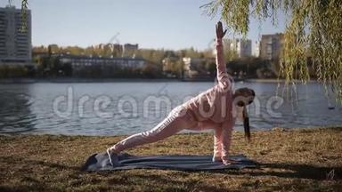 现代大都市长廊上的瑜伽.. 穿着运动服的女孩在河上瑜伽垫上。